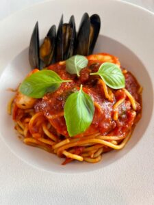 Freshly prepared spaghetti with mussels, tomato sauce, and basil leaves.