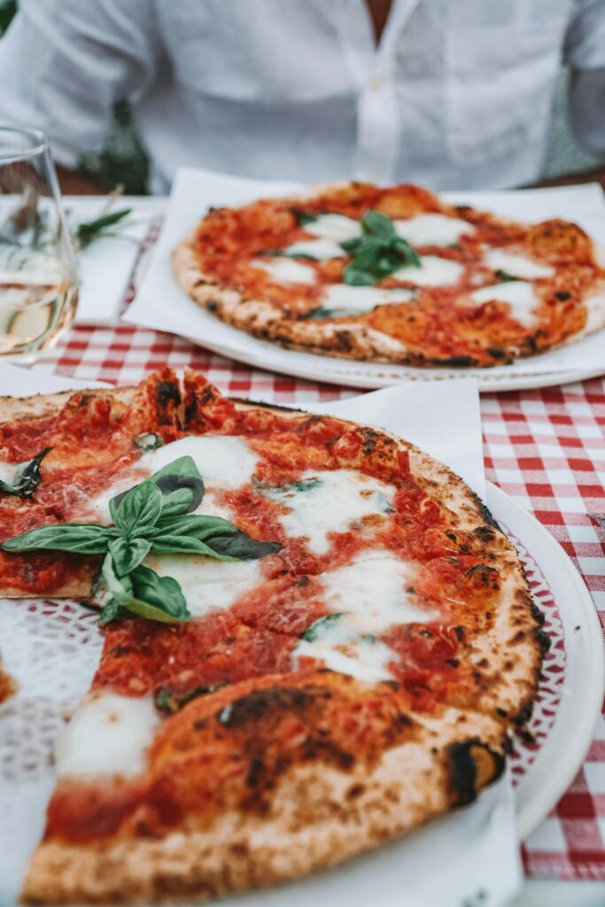 Delicious Margherita pizza with fresh basil on a red checkered tablecloth, capturing an authentic Italian dining experience.