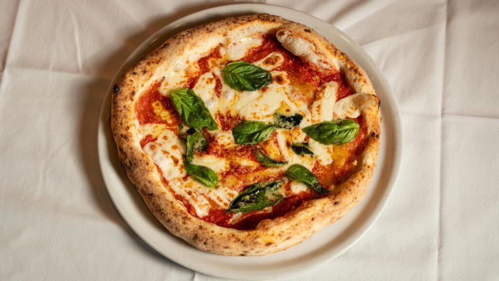 Classic Neapolitan Margherita pizza topped with fresh basil, mozzarella, and tomato sauce.